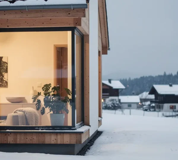 Moderne Minergie-P-Architektur in der Schweiz im Winter: aussen Schnee und kaltes Licht, innen warmes, ruhiges Wohnambiente mit viel leerem Raum fuer eine Ueberschrift.